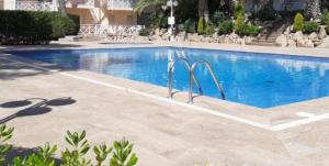 une grande piscine dans un complexe avec des chaises et un bâtiment dans l'établissement Noemar, à Platja d'Aro