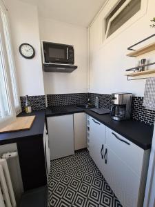 a small kitchen with black counters and a microwave at Vivez Le Centre ville à la Plage - Balcon in Le Havre