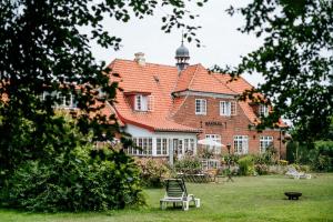 ein großes Backsteinhaus mit Rasen davor in der Unterkunft Langebjerg Pension & Spisested in Allinge