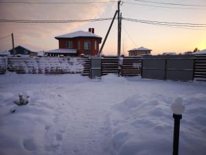 a yard covered in snow with a house in the background at Коттедж "Веселый апельсин" in Yeksolovo