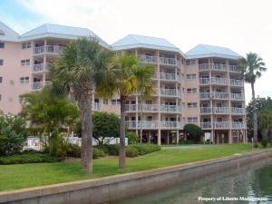 a large apartment building with palm trees next to a body of water at Sunrise Resort by Liberte' in St. Pete Beach