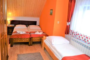 two beds in a room with orange walls at PERŁA in Białka Tatrzanska +40 photos