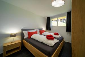 Schlafzimmer mit einem Bett mit roten Kissen und einem Fenster in der Unterkunft Chalet Altishofen in Riederalp