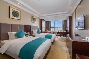 een hotelkamer met 2 bedden en een bureau bij Huzhou Wealth Hotel in Huzhou