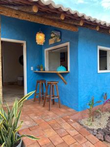 Uma casa azul com bancos à frente. em Vilarejo Macapá Chalés em Luís Correia