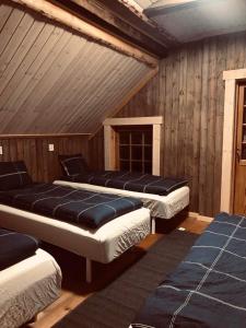 three beds in a room with wooden walls at Storbo Adventure Camp in Storbo