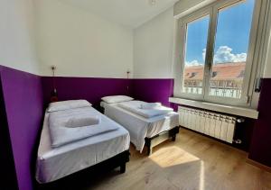 2 camas en una habitación con paredes moradas y blancas en Hotello Hostel, en Trieste