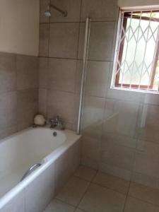 ein Bad mit einer Badewanne und einem Fenster in der Unterkunft 19 Mirabelle Place in Pietermaritzburg