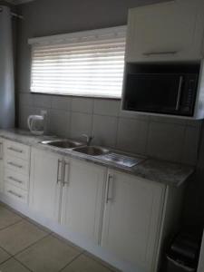 a kitchen with a sink and a microwave at 19 Mirabelle Place in Pietermaritzburg