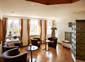 a waiting room with tables and chairs and windows at Hotel Wassberg in Forch