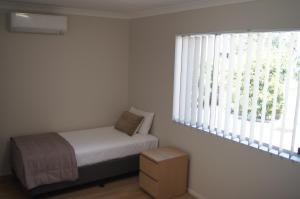 a bedroom with a bed and a window at Beachside Motor Inn in Hervey Bay