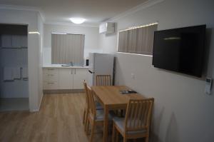 a kitchen with a table and chairs and a television at Beachside Motor Inn in Hervey Bay