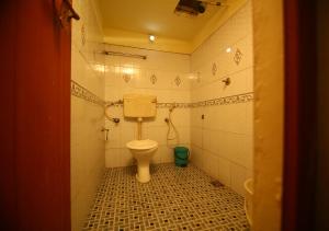 a bathroom with a toilet and a green bucket at Royal Holidays in Alleppey