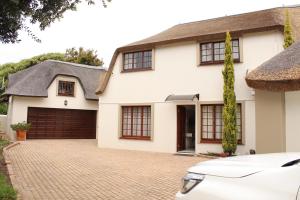 una casa blanca con garaje en Windfall Plett, en Plettenberg Bay