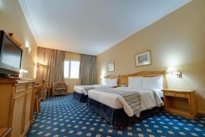 a hotel room with two beds and a flat screen tv at Grand Continental Hotel in Abu Dhabi