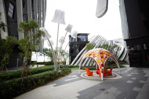 einen Garten mit Stühlen und einem Sonnenschirm in einer Stadt in der Unterkunft Near MITEC, Arte Mont Kiara by Cobnb in Kuala Lumpur