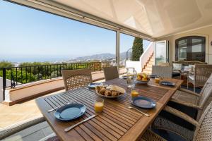 a wooden table with a plate of food on a balcony at Villa Nerja Views Mediterranean Panorama in Nerja