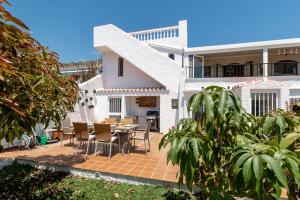 Casa blanca con patio con mesa y sillas en Villa Nerja Views Mediterranean Panorama, en Nerja