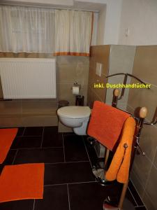 a bathroom with a toilet and orange towels at DIE Ferienwohnung - Wittenberg an den Elbwiesen in Lutherstadt Wittenberg