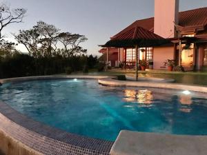a swimming pool in front of a house at Dream Villa, Ocean View & Pool! in San Ramón
