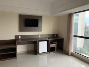 a living room with a desk and a tv on the wall at Tropical Executive Hotel flat in Manaus