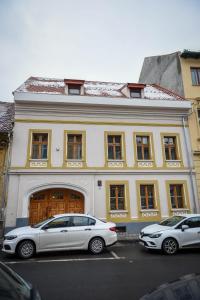 two cars parked in front of a large building at Schloss Apartments in Braşov