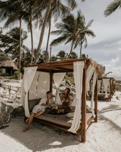 a man sitting on top of a tent in the sand at Diamante K in Tulum