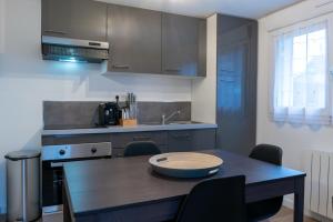 a kitchen with a table and chairs and a kitchen with a sink at Bel appartement idéalement placé Saint-Brieuc, wifi, parking gratuit in Saint-Brieuc