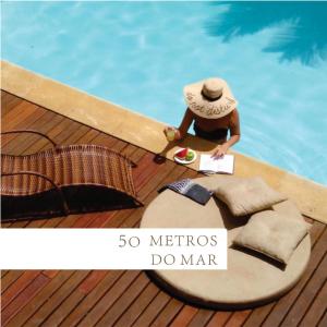 un hombre sentado en una terraza junto a una piscina en Morada do Sol Guest House, en Búzios