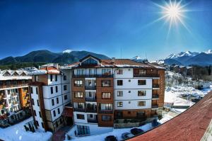 a building in the snow with mountains in the background at 50m from Ski Piste 1 BR Apartment in Predela 2 in Bansko