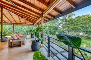 Habitación con balcón con sofá y plantas. en Yoshi's on the beach, en Cahuita