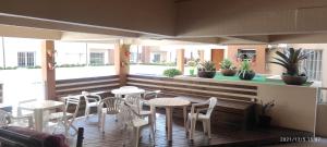un restaurante con mesas blancas y sillas en una terraza en Apartamento Capão Novo, en Capão da Canoa