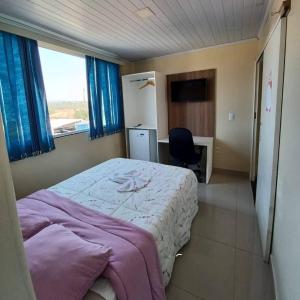 a bedroom with a bed and a desk and a window at Hotel Brasília - centro in Brasília