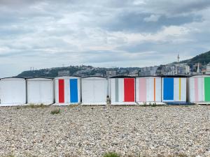 uma fileira de cabanas de praia numa praia rochosa em Vivez Le Centre ville à la Plage - Balcon em Le Havre