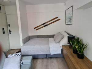 um pequeno quarto com uma cama e um sofá em Apartament pod Świerkami em Szklarska Poręba