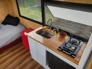 una cocina con fregadero en una casa pequeña en Quyé Tiny House, en Tenjo