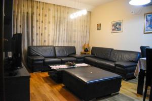 - un salon avec un canapé en cuir et une table dans l'établissement Apartman Sara 2, à Podgorica