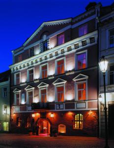 - un grand bâtiment avec des fenêtres éclairées et une lumière de rue dans l'établissement NARUTIS hotel, à Vilnius