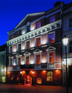 um grande edifício com janelas iluminadas e uma luz de rua em NARUTIS hotel em Vilnius