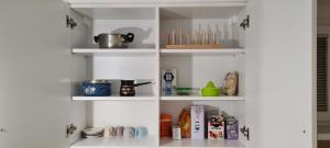 a white kitchen shelves with food items on them at Dino's spacious place in Sarajevo