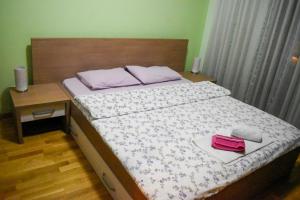 - une chambre avec un lit doté d'une tête de lit en bois dans l'établissement Apartman Sara 2, à Podgorica