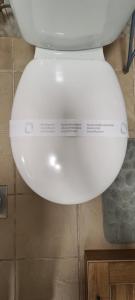 a white toilet seat with a sign on it at Dino's spacious place in Sarajevo