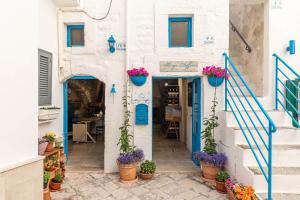a white building with blue doors and potted plants at Albergo Diffuso Monopoli in Monopoli