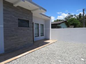 a white house with a tv on a wall at Casa do amor, vc pode ir andando até a praia in Itapoa