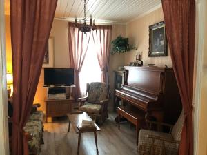 uma sala de estar com um piano e uma cadeira em La Maison des Leclerc em Trois-Rivières