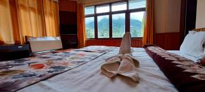 una habitación de hotel con una cama con un par de zapatos. en Le Coxy Resort Lachung en Lachung