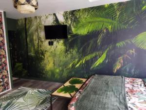 a bedroom with a wall with a mural of palm trees at Spa Mensignac in Mensignac