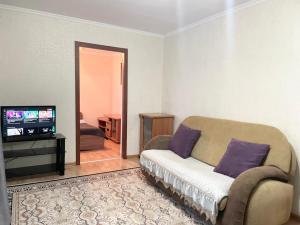 een woonkamer met een bank en een televisie bij Apartment on Astana 12/1 in Öskemen