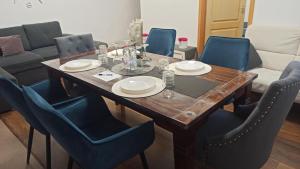 a wooden table with blue chairs and a dining room at Váralja Apartman in Tata