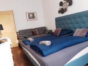 Una cama grande con sábanas azules y almohadas. en Váralja Apartman en Tata